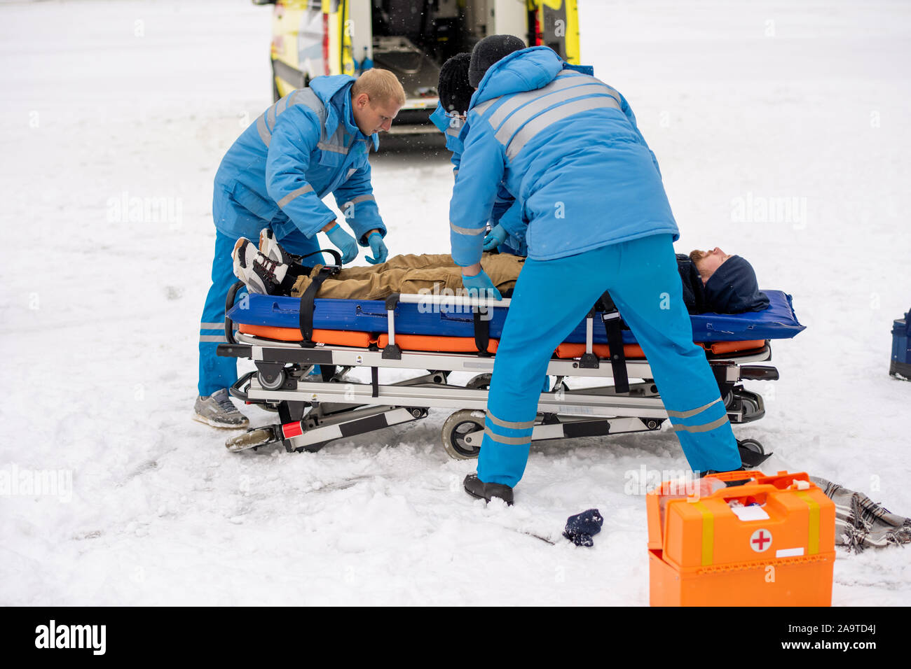I paramedici inconscio di fissaggio uomo sulla barella per arrivare a lui di ambulanza Foto Stock