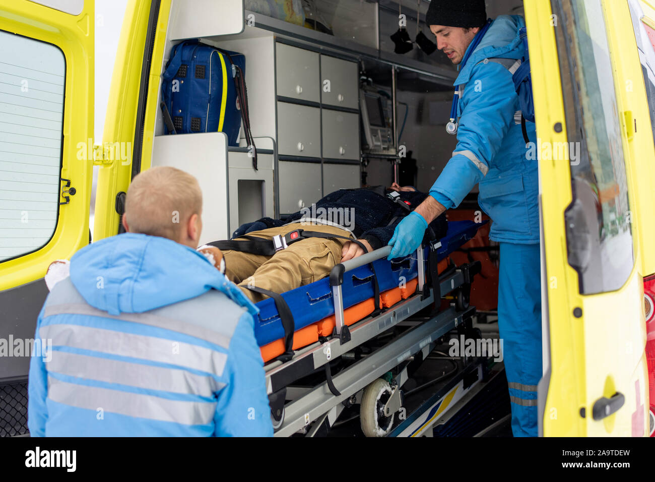 I paramedici in spinta uniforme barella con inconscio uomo in ambulanza Foto Stock