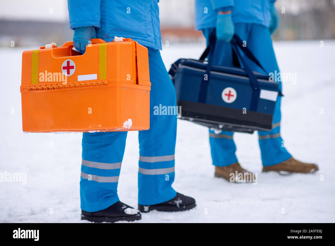 Sezione bassa di due paramedici in uniforme e guanti che trasportano kit di primo soccorso Foto Stock