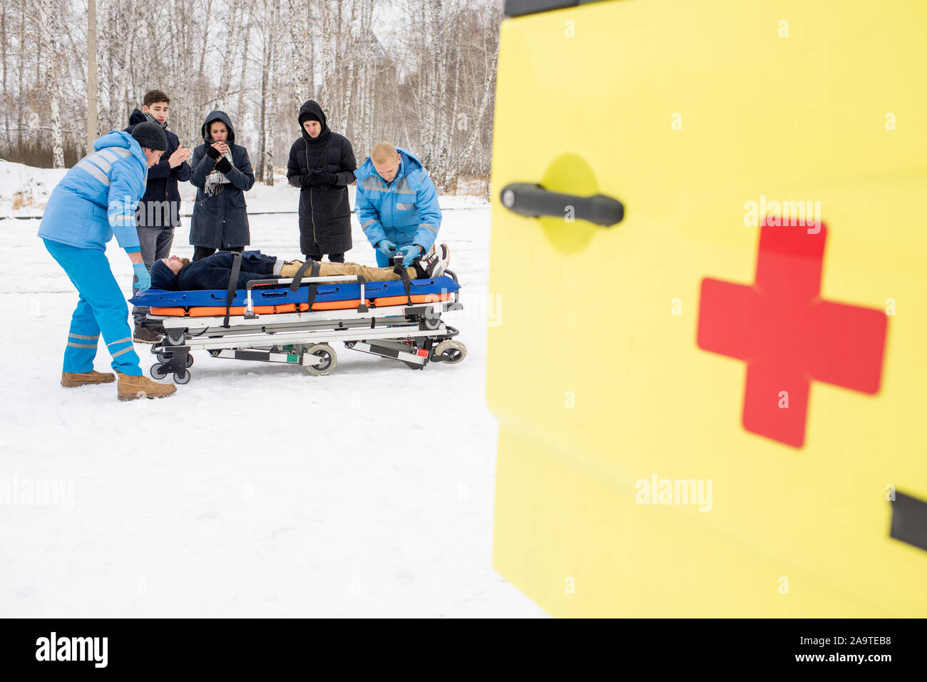 I paramedici e i giovani la piegatura su barella con fisso uomo incosciente Foto Stock