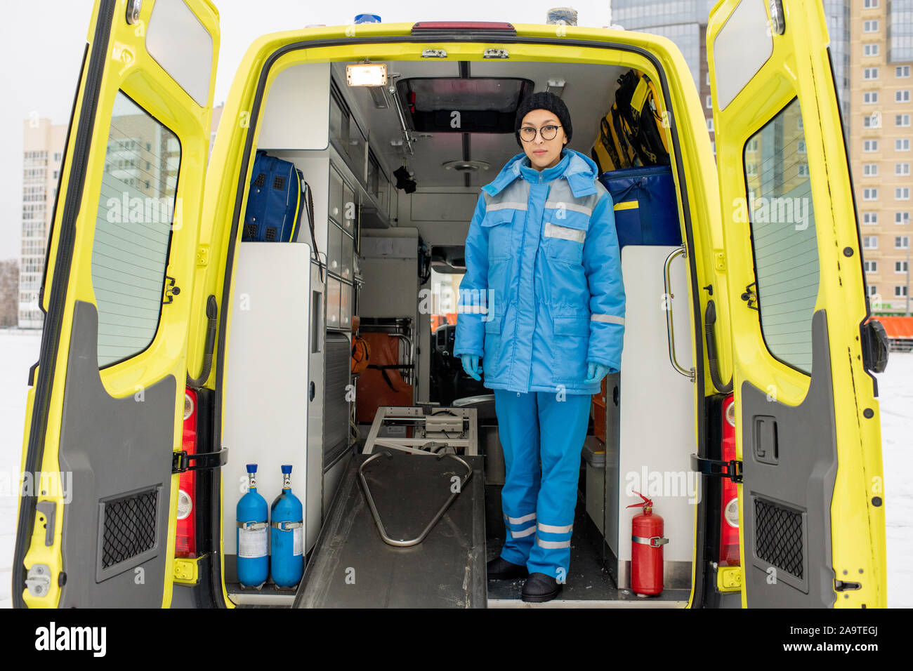 Giovani femmine paramedico in uniforme in piedi da barella vuota in ambulanza Foto Stock