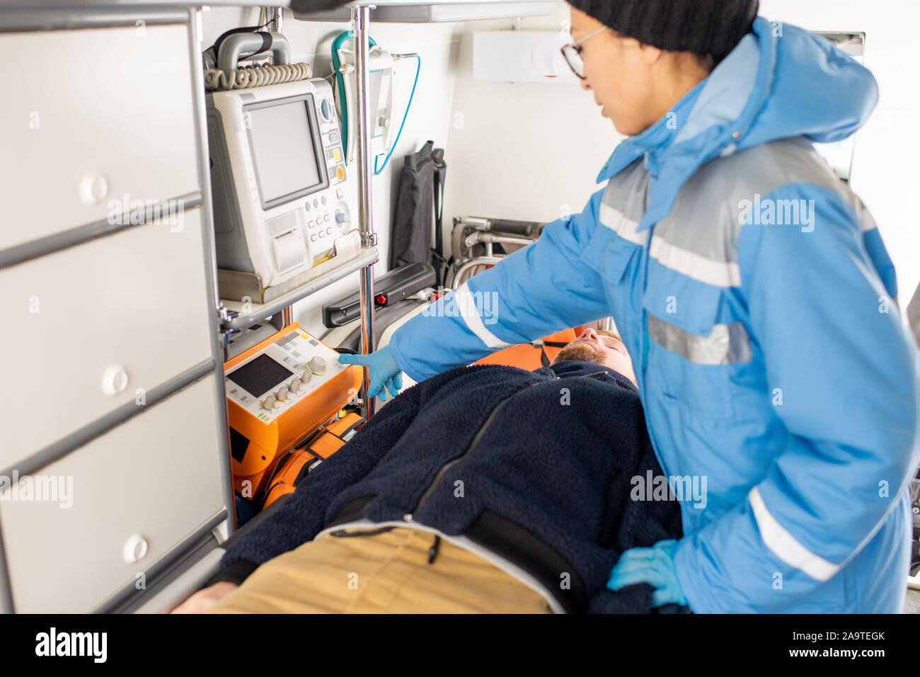 Giovane paramedico in uniforme premendo il pulsante sul medical le attrezzature di pronto soccorso Foto Stock
