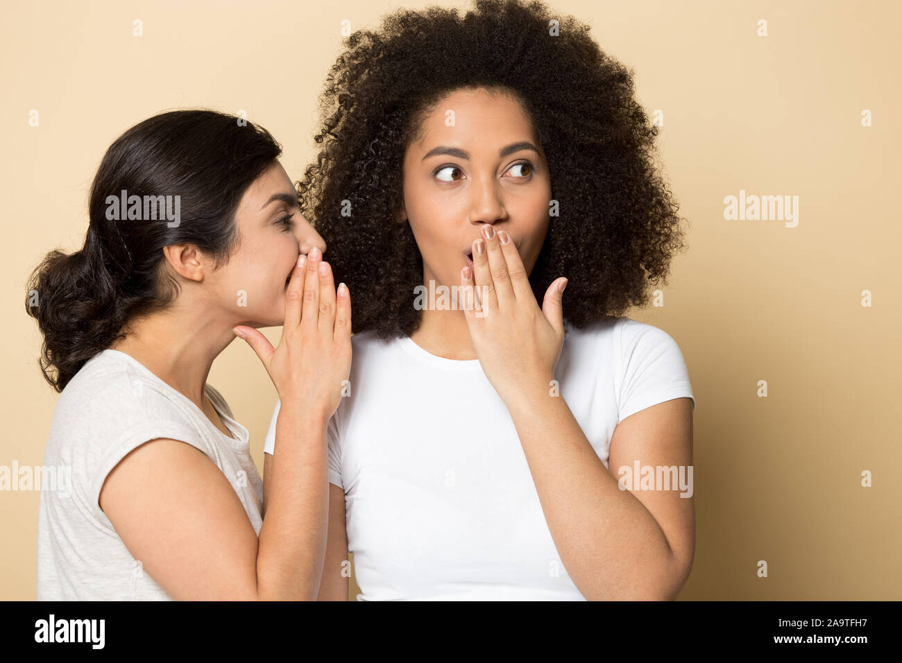 Ragazza indiana raccontando segreto per sorpreso storditi amico close up Foto Stock