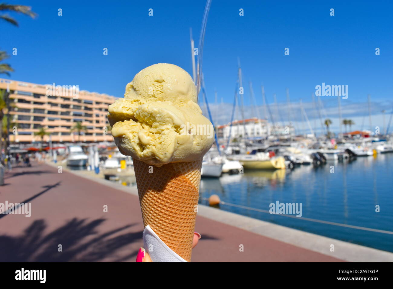 La mano della bambina azienda stile francese di gelato dalla marina nel sud del resort di Saint-Cyprien. Aromatizzato al pistacchio gelato in un cono di cialda.Soleggiato. Foto Stock