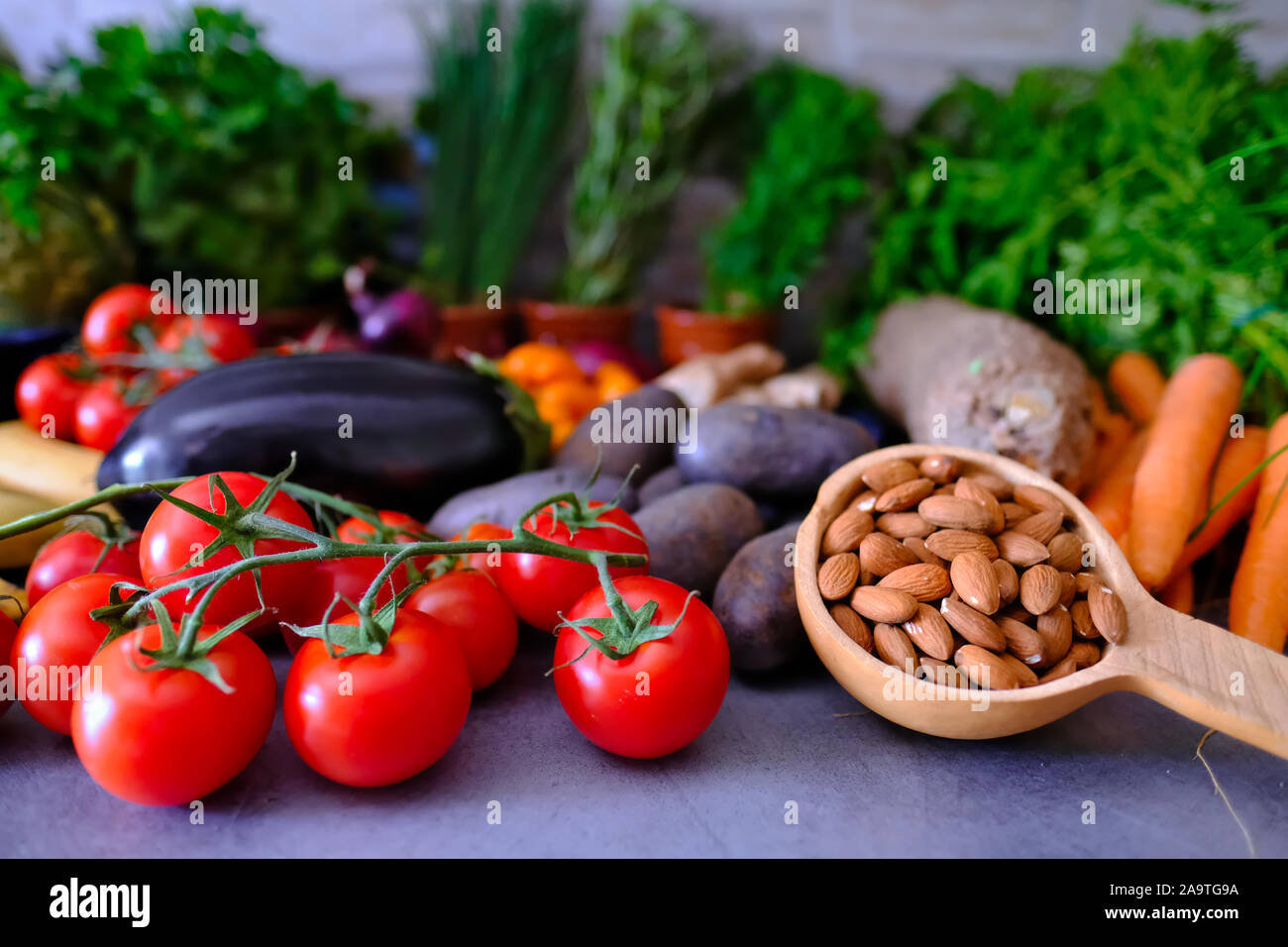 Tazza di mandorle e pomodori freschi circondato da un sacco di altre gustose verdure Foto Stock