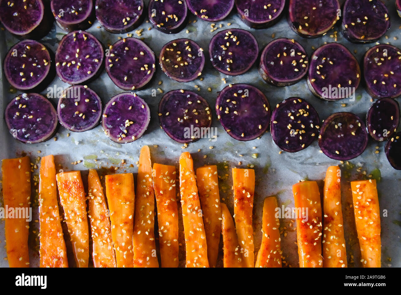 Fette di viola le patate dolci cosparsi di semi di sesamo e le carote affettate Foto Stock