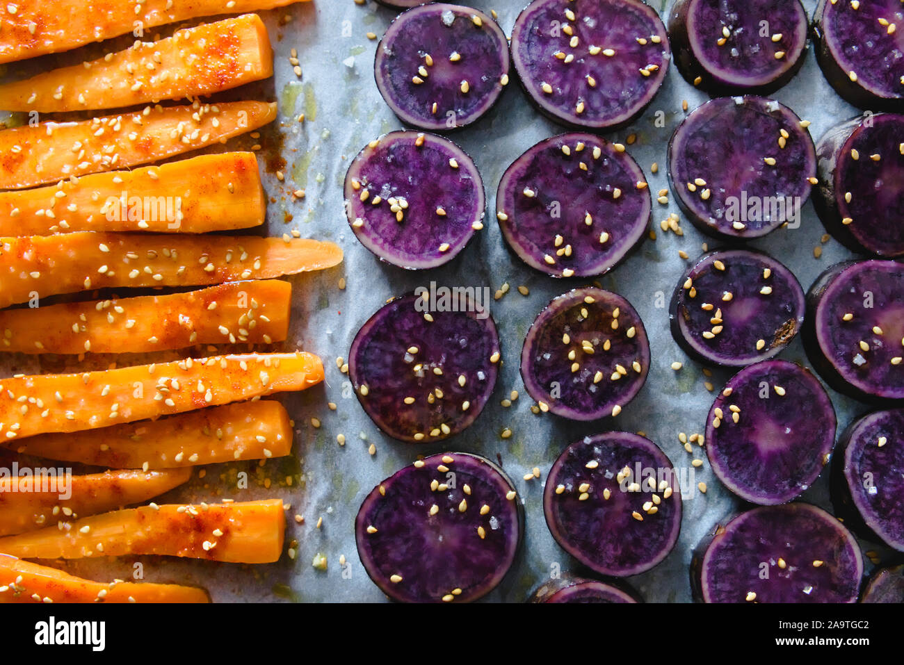 Fette di viola le patate dolci cosparsi di semi di sesamo e carote Foto Stock