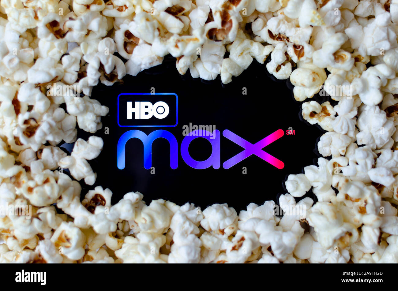 HBO max logo su uno smartphone coperti con popcorn. Foto di concetto per un nuovo servizio di streaming di video. Foto Stock