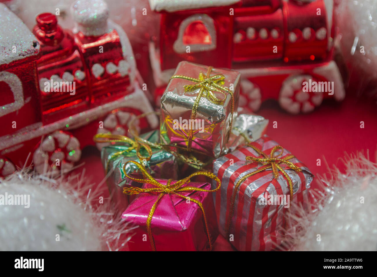 Ornamenti in treno rosso con regali di Natale su sfondo rosso, foto-illustrazione Foto Stock