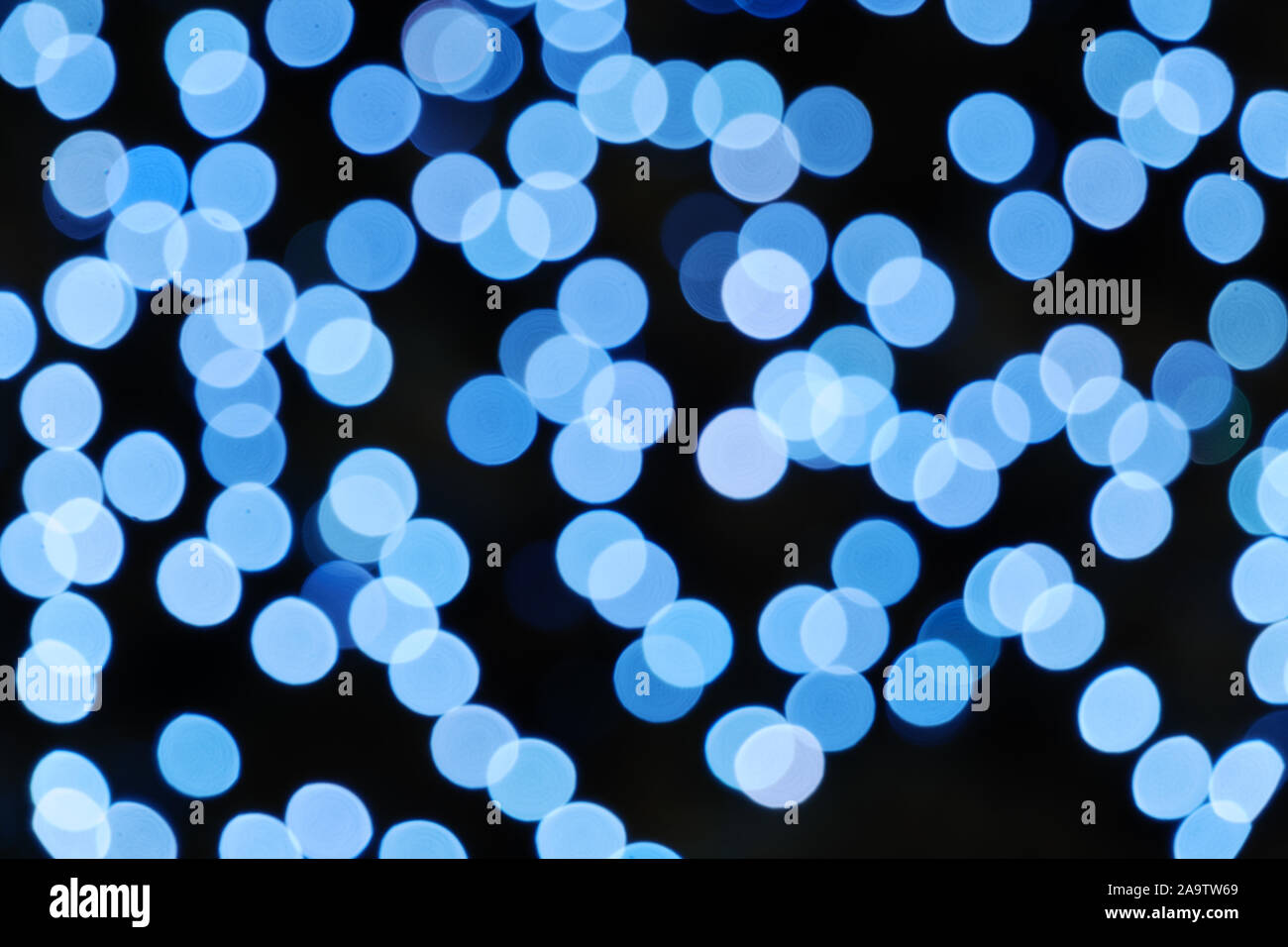Illuminato rotondo astratta profondo blu e viola bokeh su sfondo scuro. Coloratissimo glitter bokeh da fuori fuoco vista della decorazione delle lampadine. Foto Stock