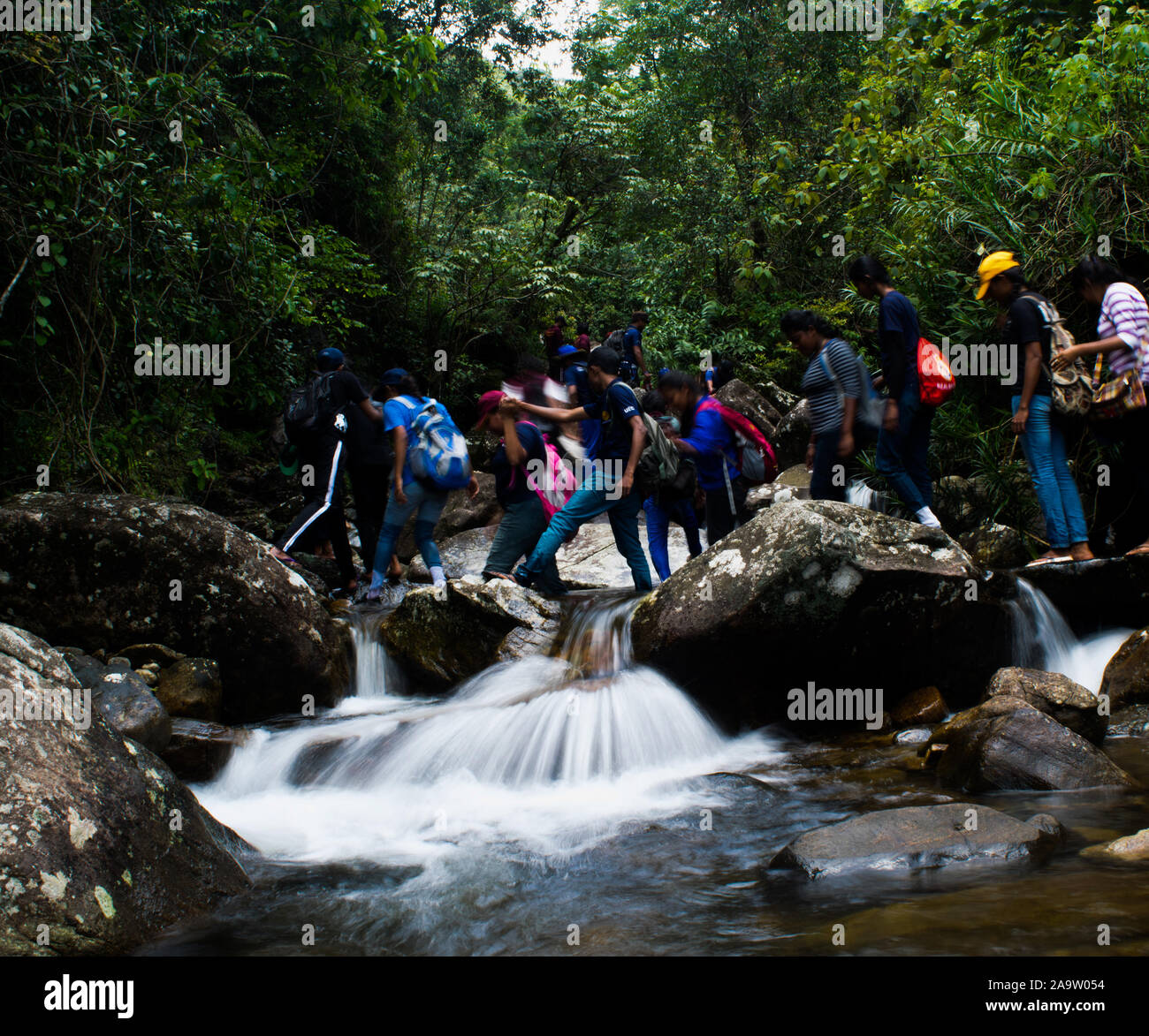 Maggio, 2008 , Kandy , Sri Lanka , squadra di giovani attraversano il flusso di acqua. Foto Stock