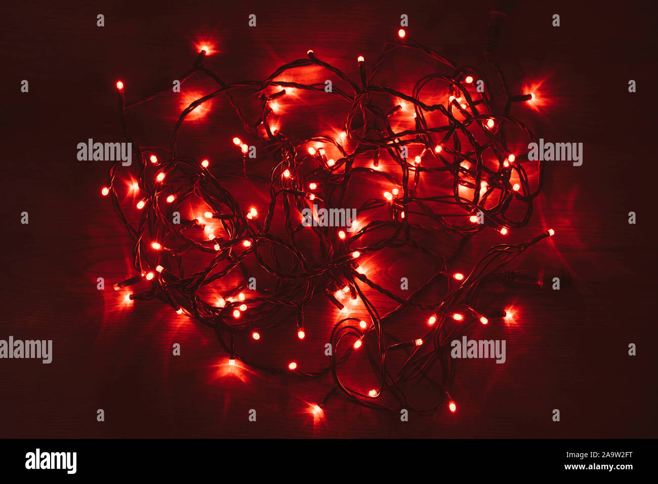 Red le luci di Natale su una tavola di legno. Brilla di un colore rosso brillante. Disorganizzati luci LED rosse. Foto Stock