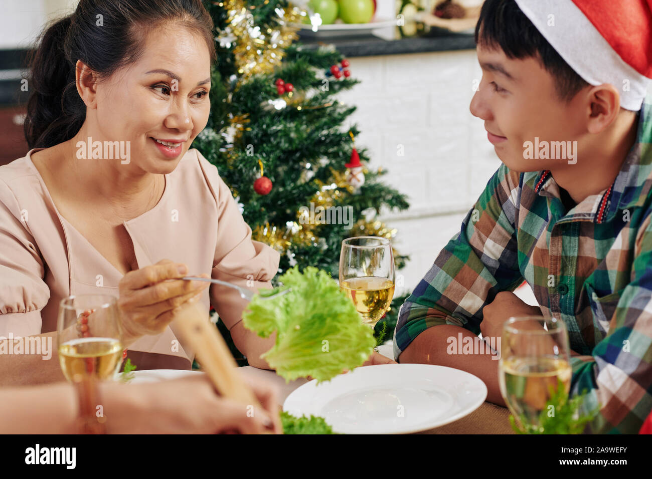 Senior donna asiatica parlando a suo nipote adolescente a cena di Natale Foto Stock