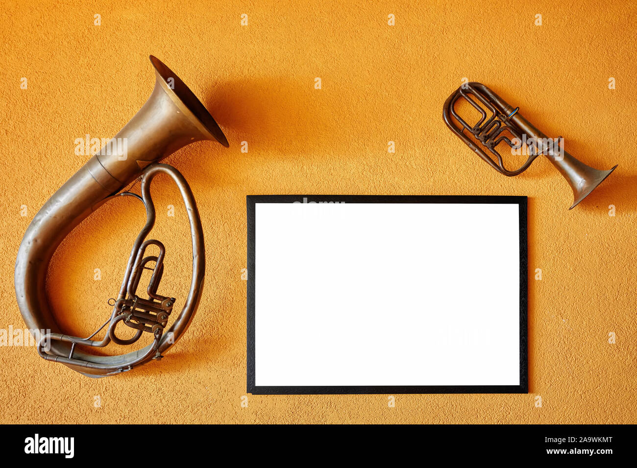 Vintage corno francese, una tromba e un telaio vuoto appesi al giallo della parete interna di un jazz cafe Foto Stock