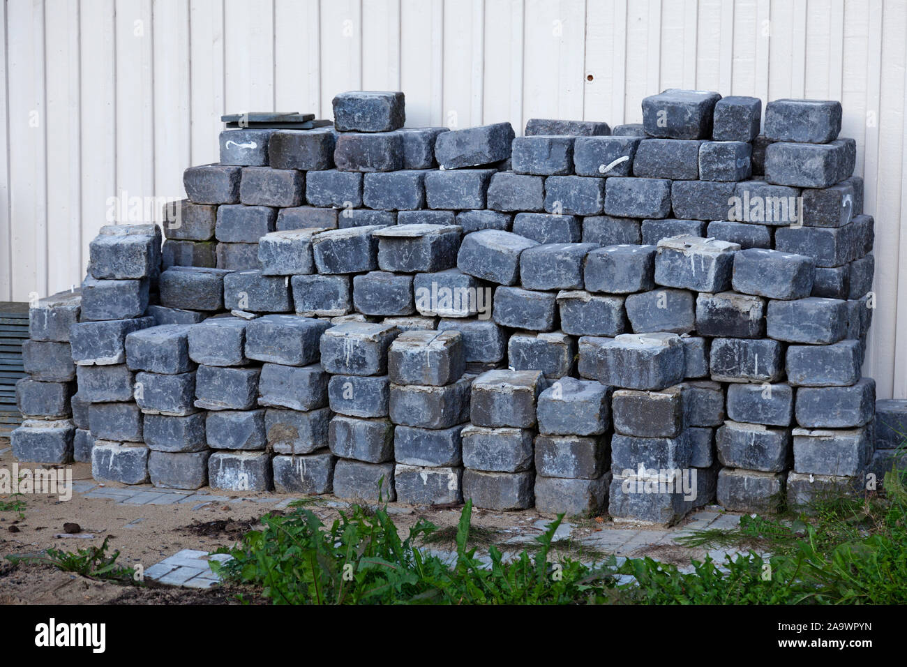 Pietre per pavimentazione accatastati in pile al muro di casa per la costruzione del viale di accesso al garage Foto Stock