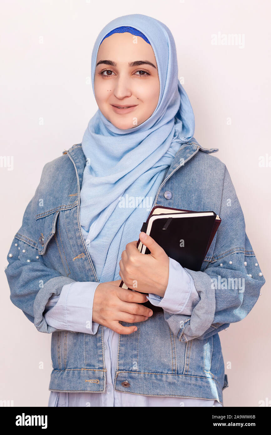 Ritratto di carino imprenditrice musulmana. Attraente studente musulmano quaderni di contenimento. Bella ragazza musulmana nel tradizionale hijab islamico e camicia denim. M Foto Stock