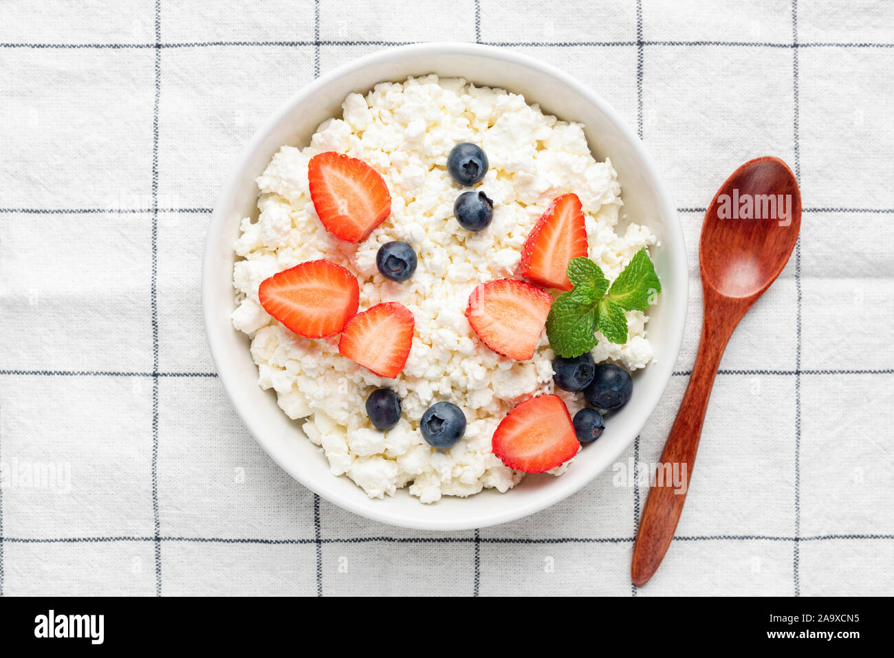 In casa cottage cheese, ricotta o tvorog con frutti di bosco freschi in vaso su sfondo tessili. Vista dall'alto. Caseificio sano prodotto, pulire il concetto di mangiare Foto Stock