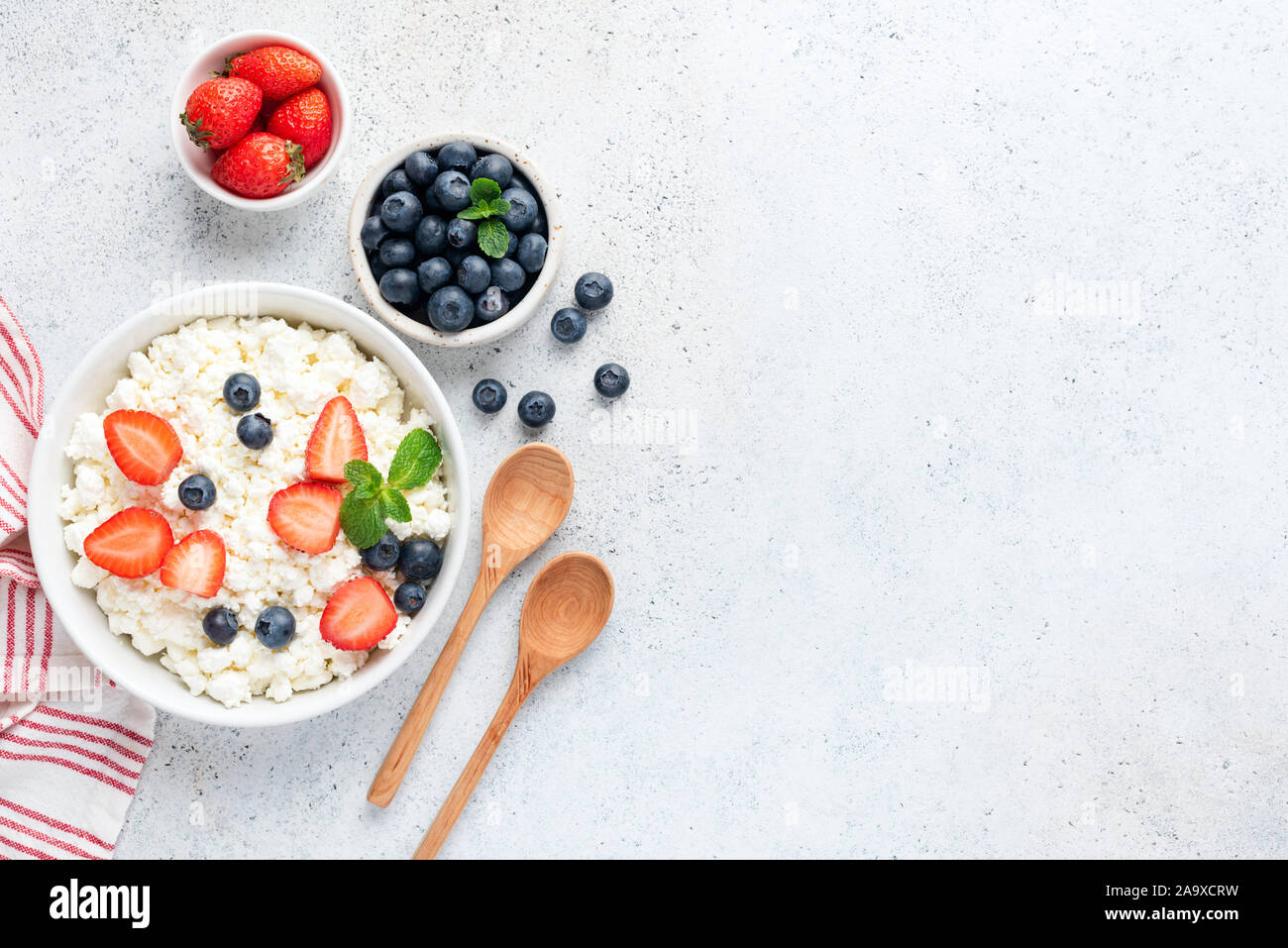 Ricotta, formaggio tvorog o o ricotta con frutti di bosco freschi in vaso su sfondo di calcestruzzo. Caseificio sano prodotto, fonte di calcio e di prote Foto Stock