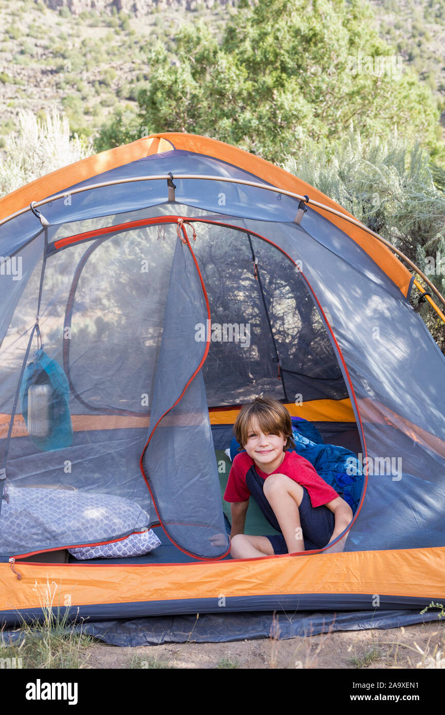 Ritratto di 6 anno vecchio ragazzo seduto in una tenda Foto Stock