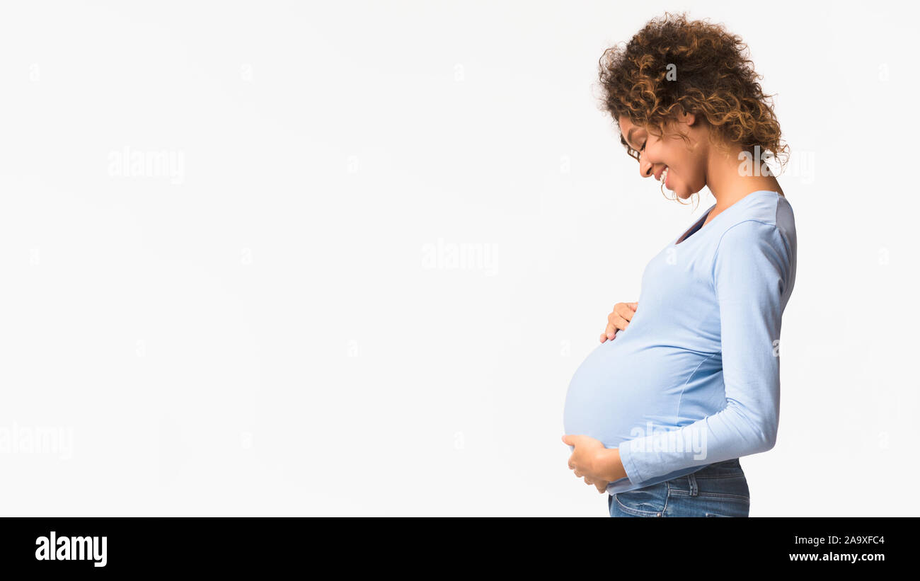 Godendo di maternità. Afro donna incinta abbracciando il suo ventre Foto Stock