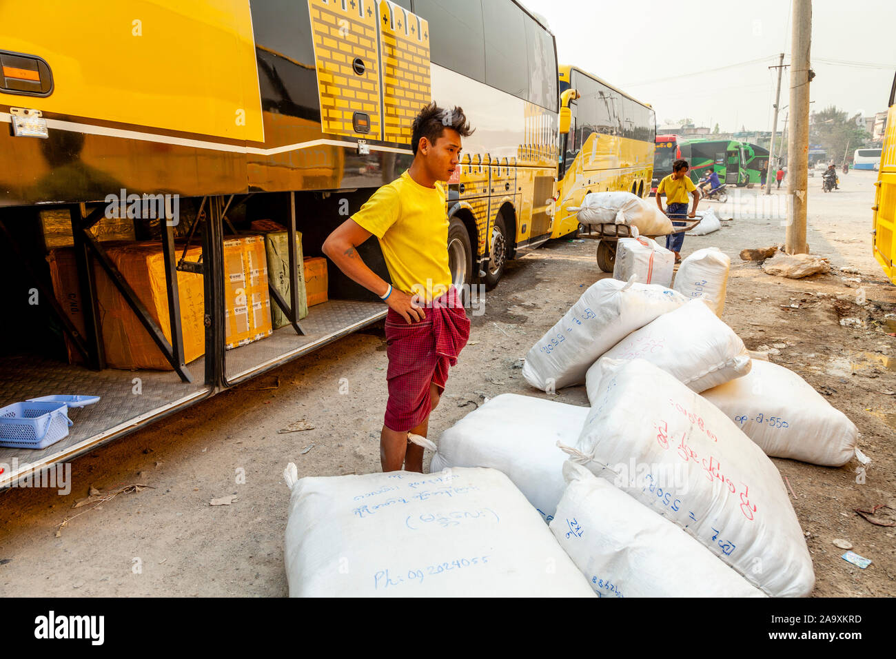 Giovani uomini il carico delle merci su un bus, Mandalay alla stazione degli autobus, Mandalay Myanmar. Foto Stock