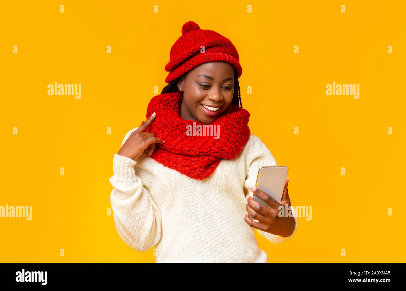 Allegro nero ragazza in inverno rosso hat tenendo selfie Foto Stock