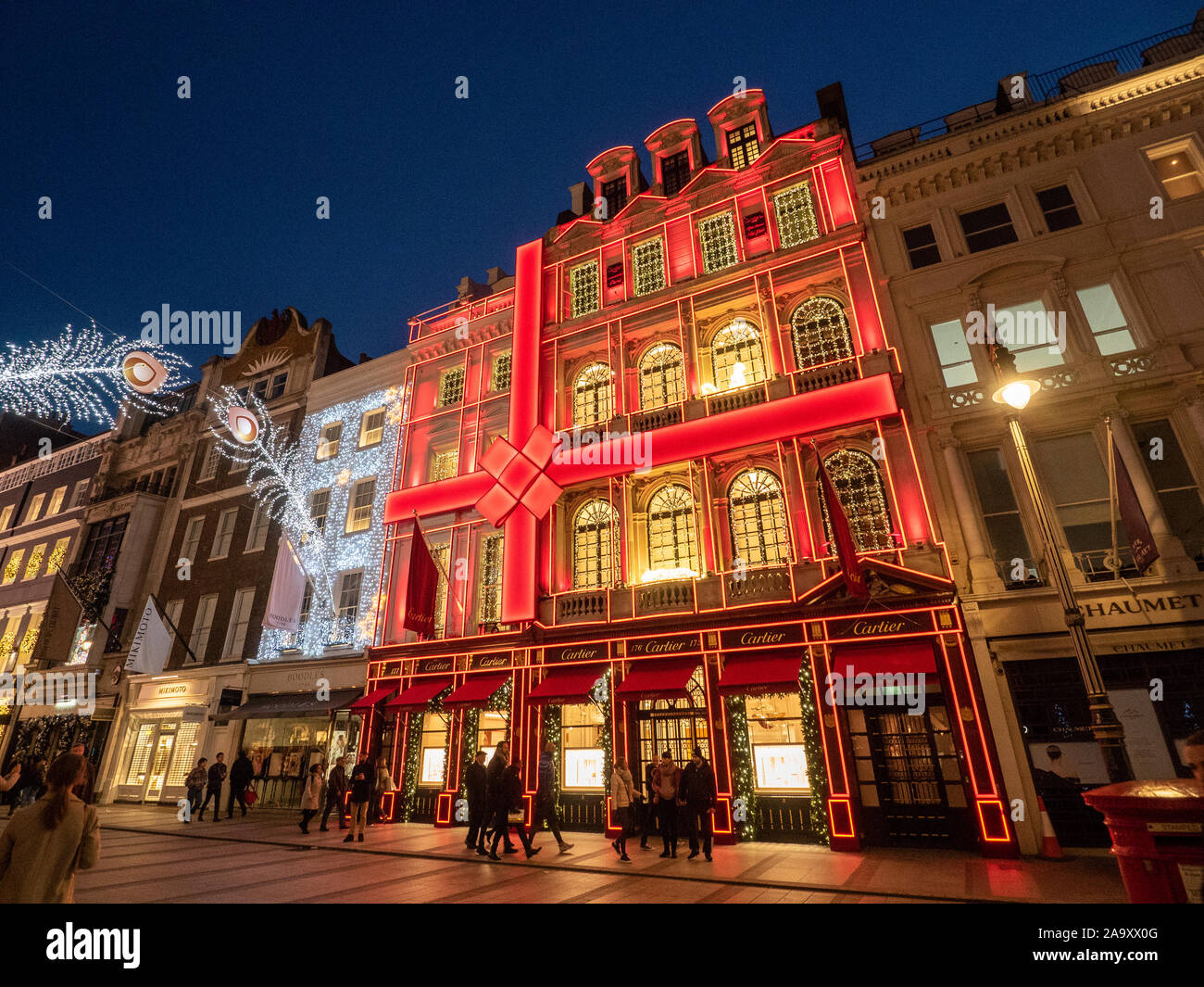Luci festive in New Bond Street di notte con la facciata rossa di Cartier, Mayfair, Londra. Foto Stock
