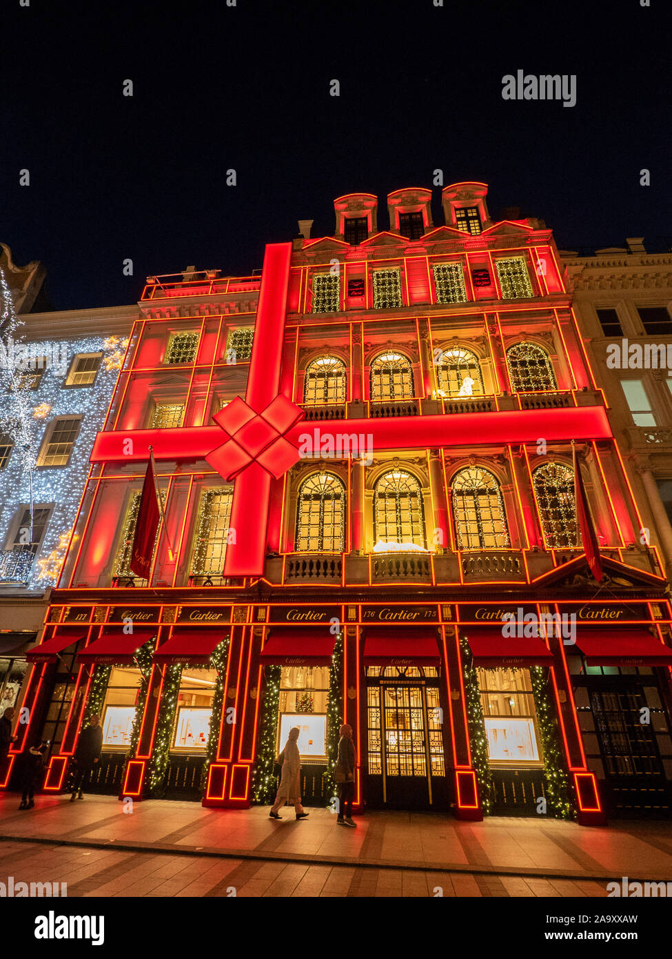 Luci festive in New Bond Street di notte con la facciata rossa di Cartier, Mayfair, Londra. Foto Stock