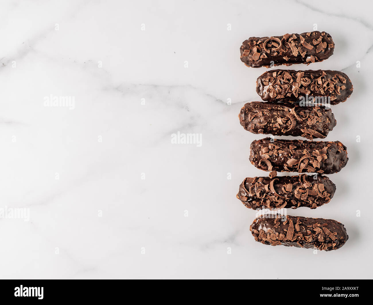 Set di eclairs fatti in casa con cioccolato su sfondo marmo. Vista superiore della deliziosa profitroles sani con glassa di cioccolato. Copia spazio per il testo o per la progettazione Foto Stock