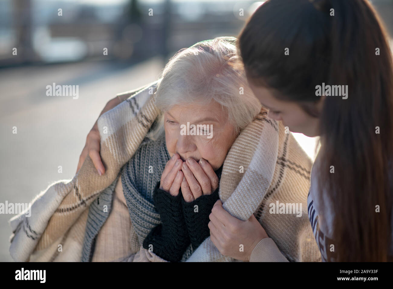 Dai capelli scuri supporto donna senzatetto pensionato pur portando il plaid Foto Stock
