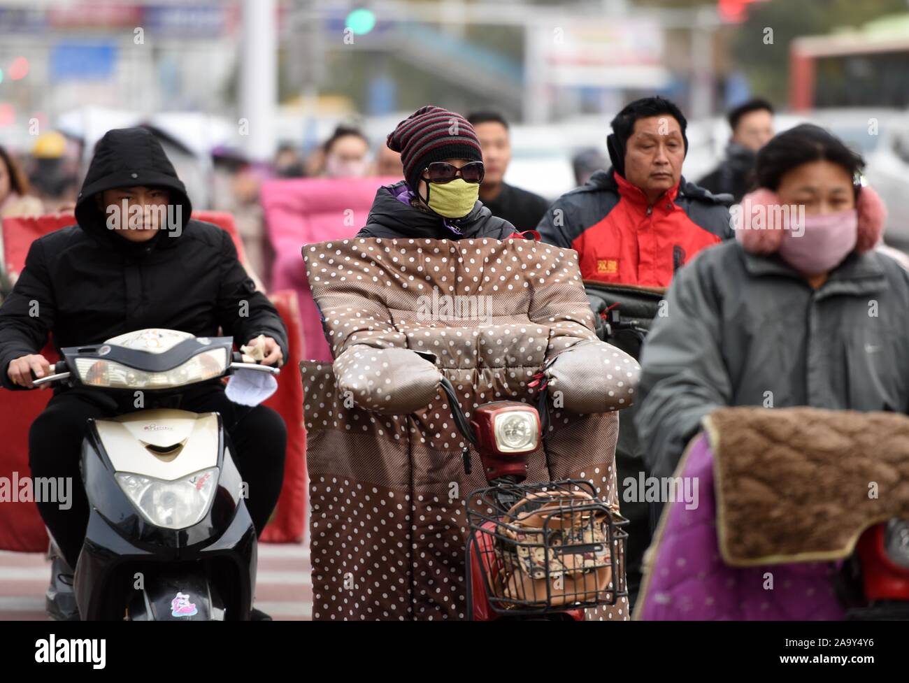 Locali residenti cinesi indossando indumenti pesanti commutare dalla bicicletta elettrica sulla strada nell'ondata di freddo in Huai'an City, est della Cina di Jiangsu Province su Foto Stock