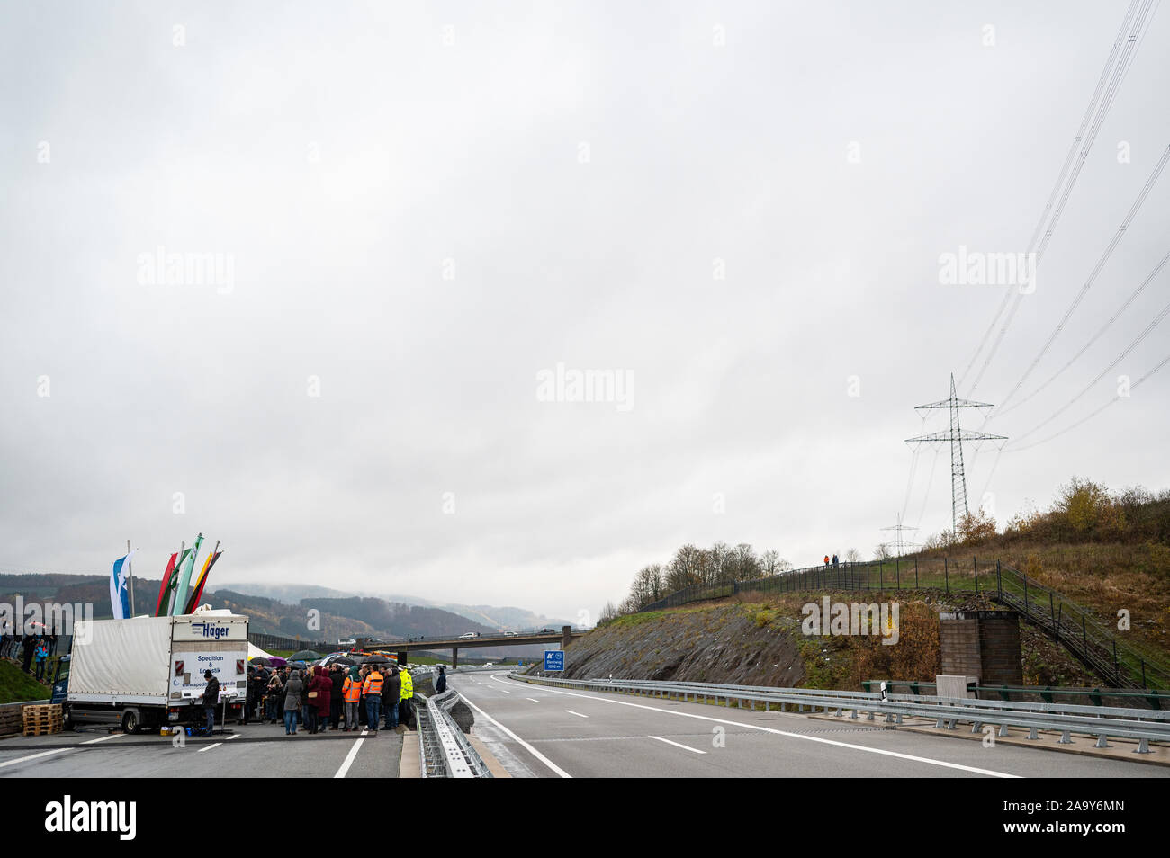 Bestwig, Germania. Xviii Nov, 2019. Presso il cerimoniale di apertura del più alto ponte autostradale in NRW, numerose persone in piedi sulla A46 vicino Bestwig. Il ponte di valle Nuttlar è il completamento di un ponte a valle nel corso dell'autostrada federale 46 nel Sauerland. Con un altezza di 115 metri, è il ponte più alto nella Renania settentrionale-Vestfalia. Oggi la sezione dell'autostrada 46 e il ponte sono stati ufficialmente inaugurato e aperto al traffico. Credito: Guido Kirchner/dpa/Alamy Live News Foto Stock