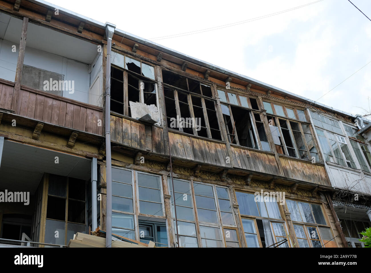 Vecchia casa con logge in legno e vetro rotto. Abbandonato non-edificio residenziale. I quartieri poveri di Tbilisi. Foto Stock