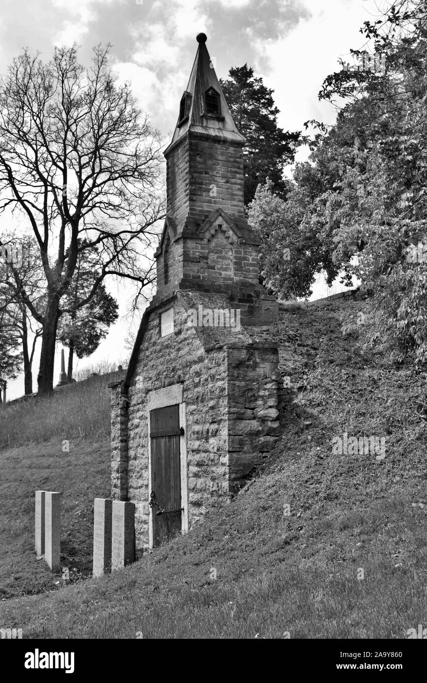 Molto vecchio mausoleo costruito sul fianco di una collina con steeple, lapidi, e ferro battuto recinzione Foto Stock