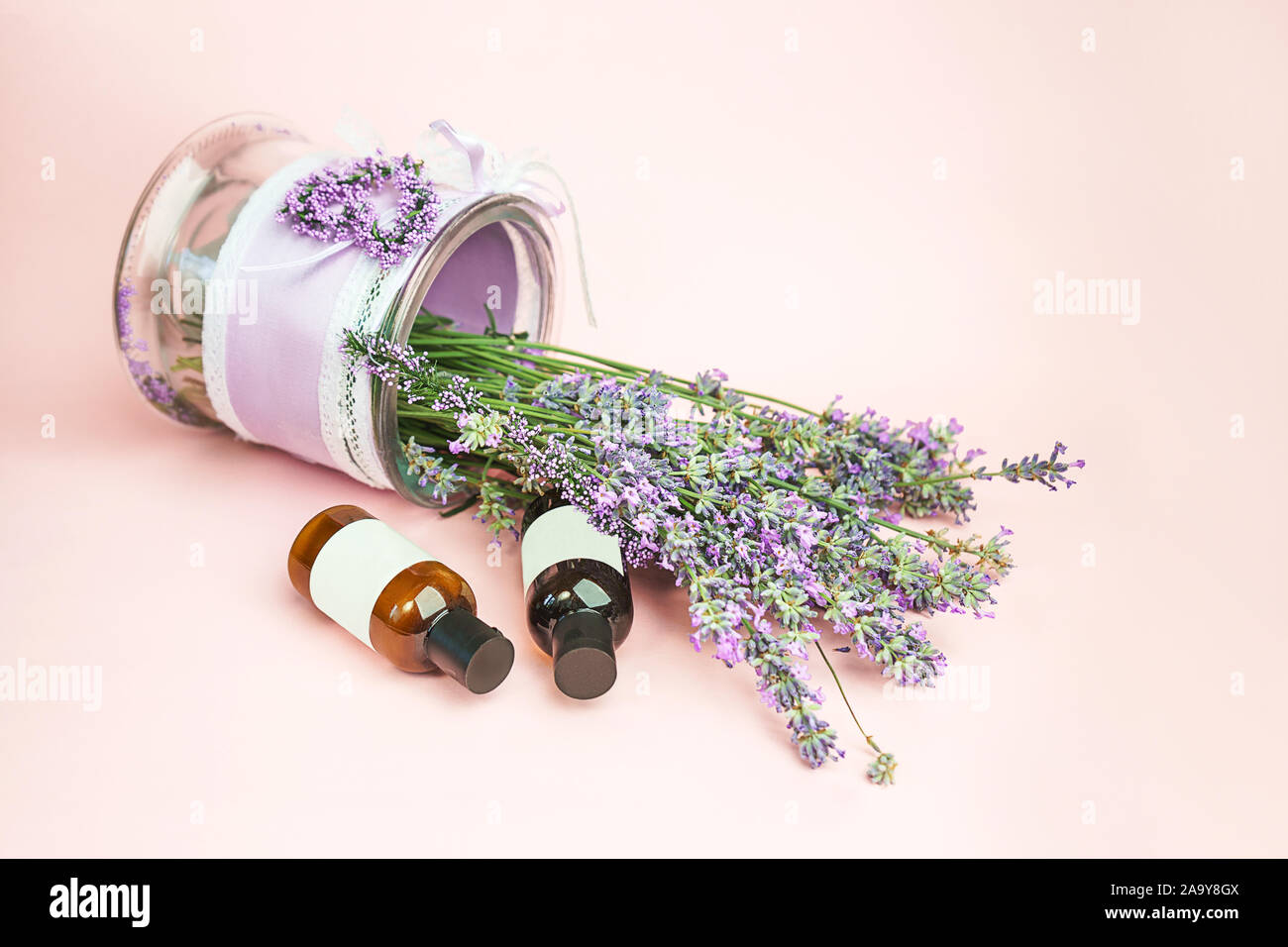 Cosmetici naturali. Freschi di fiori di lavanda e bottiglie di olio essenziale o di siero pastello su sfondo rosa. Home alternativa medicina. Close-up, in stile vintage. Foto Stock
