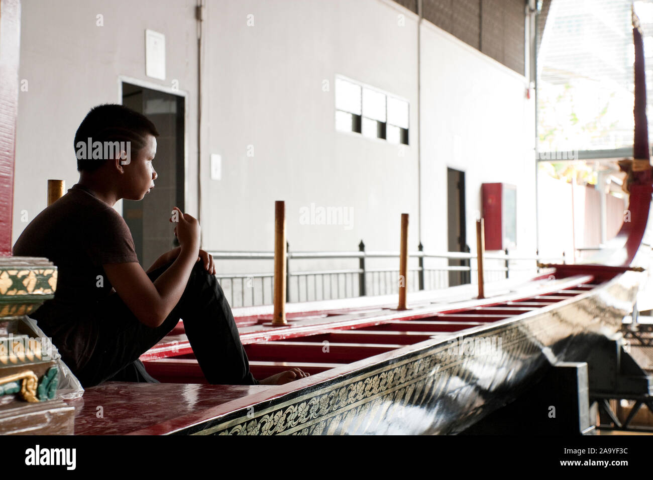 Ragazzo seduto su una delle chiatte reale il museo, Thonburi, Bangkok, Thailandia Foto Stock