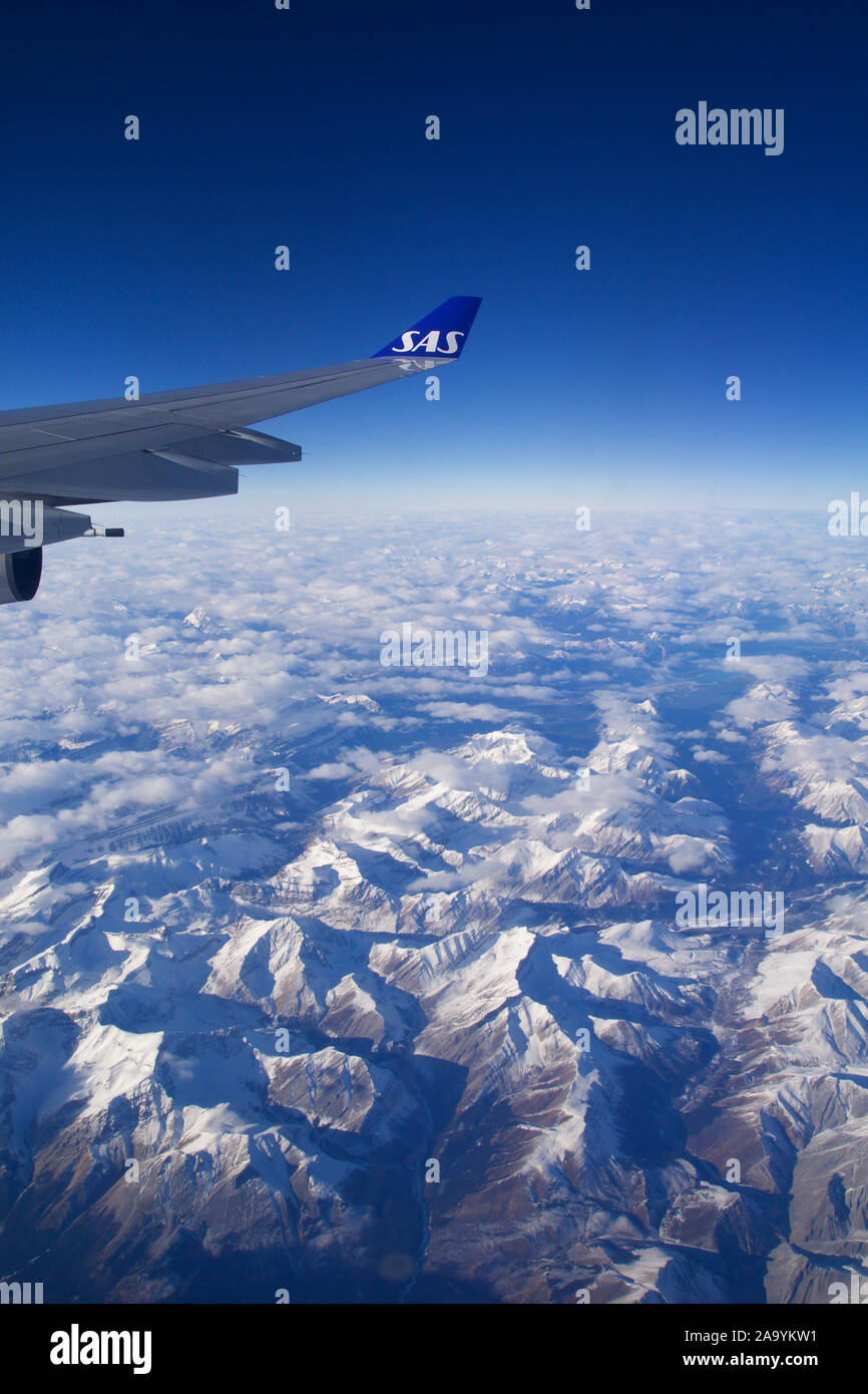 CANADA - Novembre 24th, 2018: una vista di un vasto paesaggio di montagne coperte di neve preso dalla finestra di un aereo che mostra l'ala Foto Stock