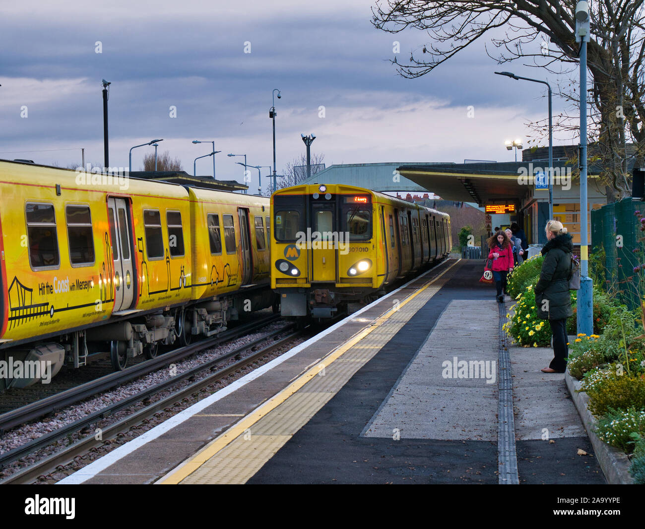 Un treno arriva come un altro treno attende sulla stazione di Hoylake sul Merseyrail elettrico ferroviario la rete di trasporto regionale rete dei " commuters " Foto Stock