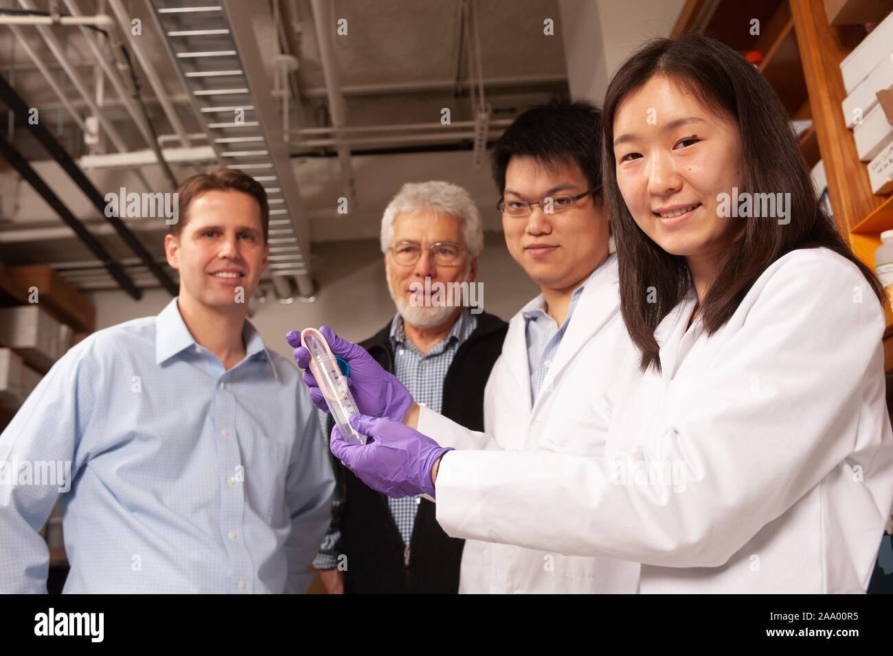 Due ricercatori indossando camici e guanti manipolare una provetta in un laboratorio presso la Johns Hopkins University di Baltimore, Maryland, mentre altri due ricercatori, tra cui il professor nanomedicine Justin Hanes (L), guarda su, 30 gennaio 2009. Dall'Homewood raccolta di fotografie. () Foto Stock
