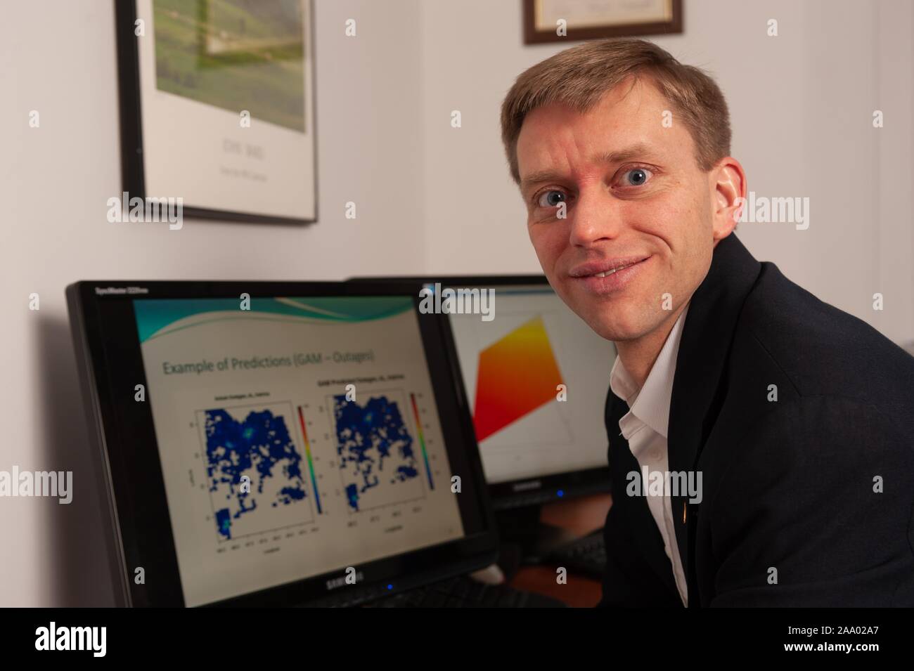 Inquadratura ravvicinata del ricercatore Seth Guikema, rivolti verso la telecamera e sorridente, con un uragano modello di predizione sullo schermo di un computer in background, presso la Johns Hopkins University, Baltimora, Maryland, Marzo 4, 2009. Dall'Homewood raccolta di fotografie. () Foto Stock