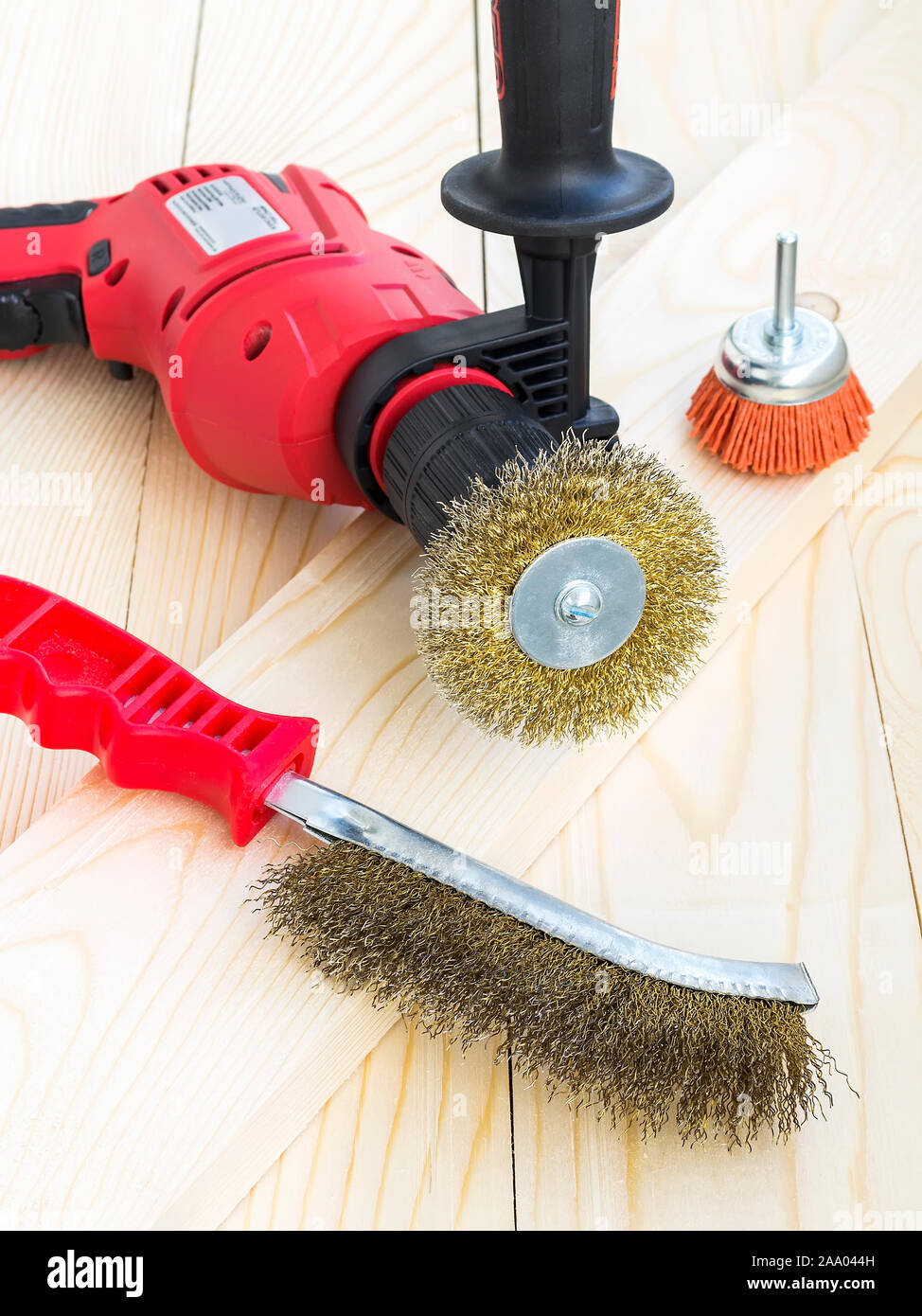 Trapano e spazzole abrasive con metallo e filo di nylon su una superficie di legno. Strumenti per la pulizia e la lucidatura e la levigatura di legno e metallo. Vista frontale. Foto Stock