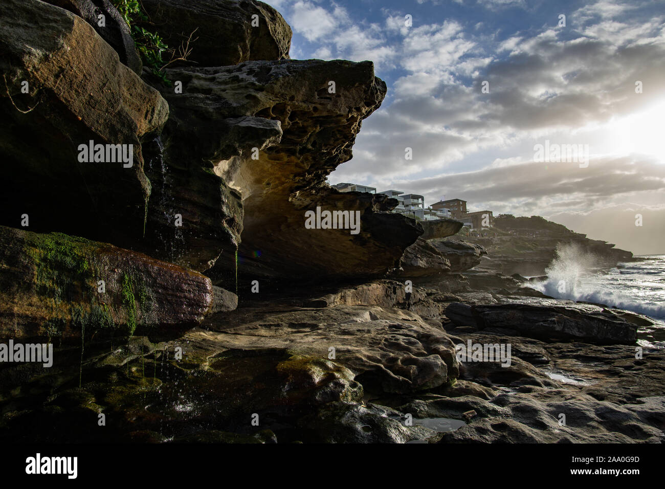 Rocce bagnate dal mare a sunrise, con case in background Foto Stock