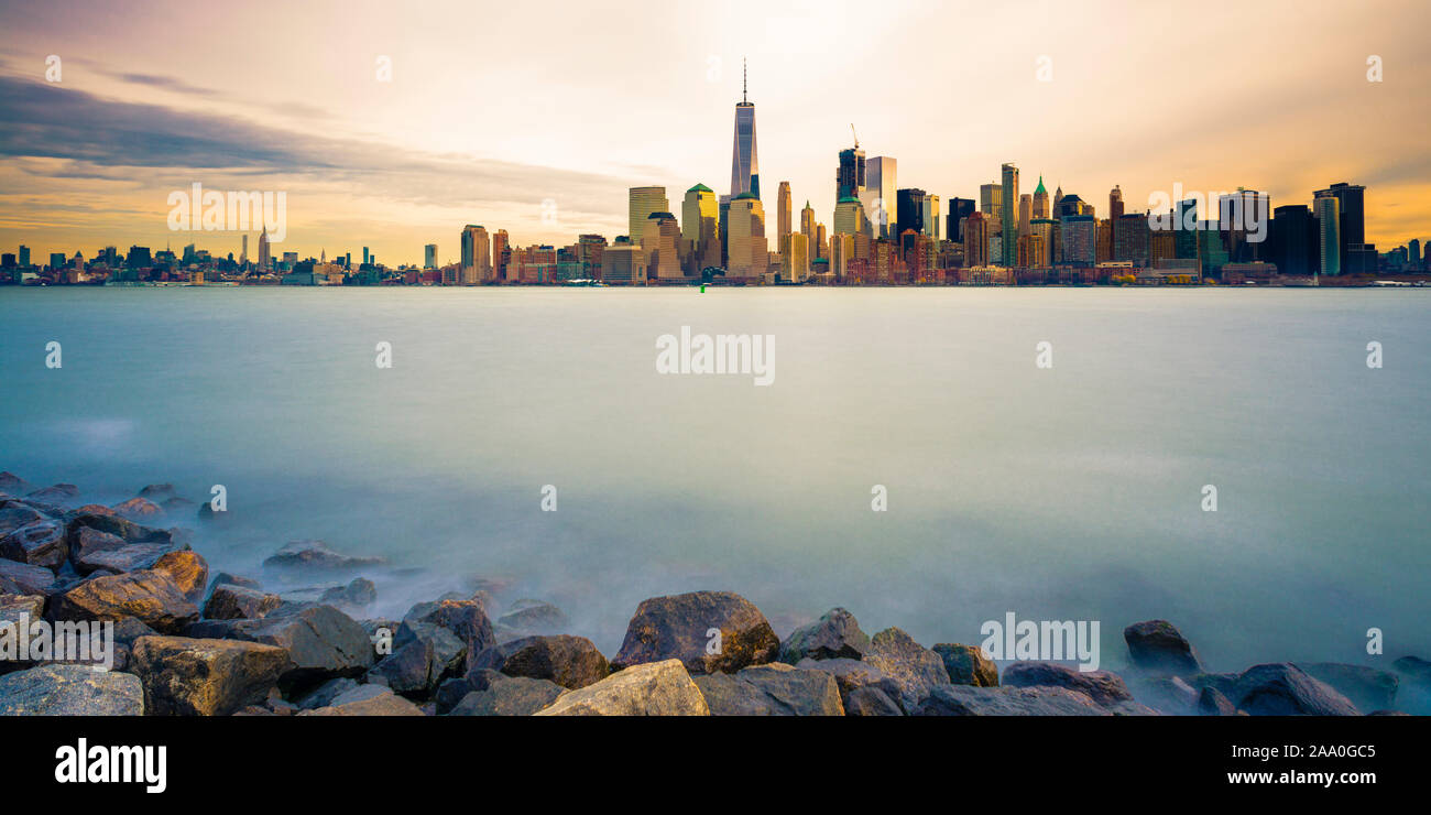 Skyline di Manhattan con acqua liscia e pietre in primo piano Foto Stock Skyline di Manhattan con acqua liscia e pietre in primo piano Foto Stock