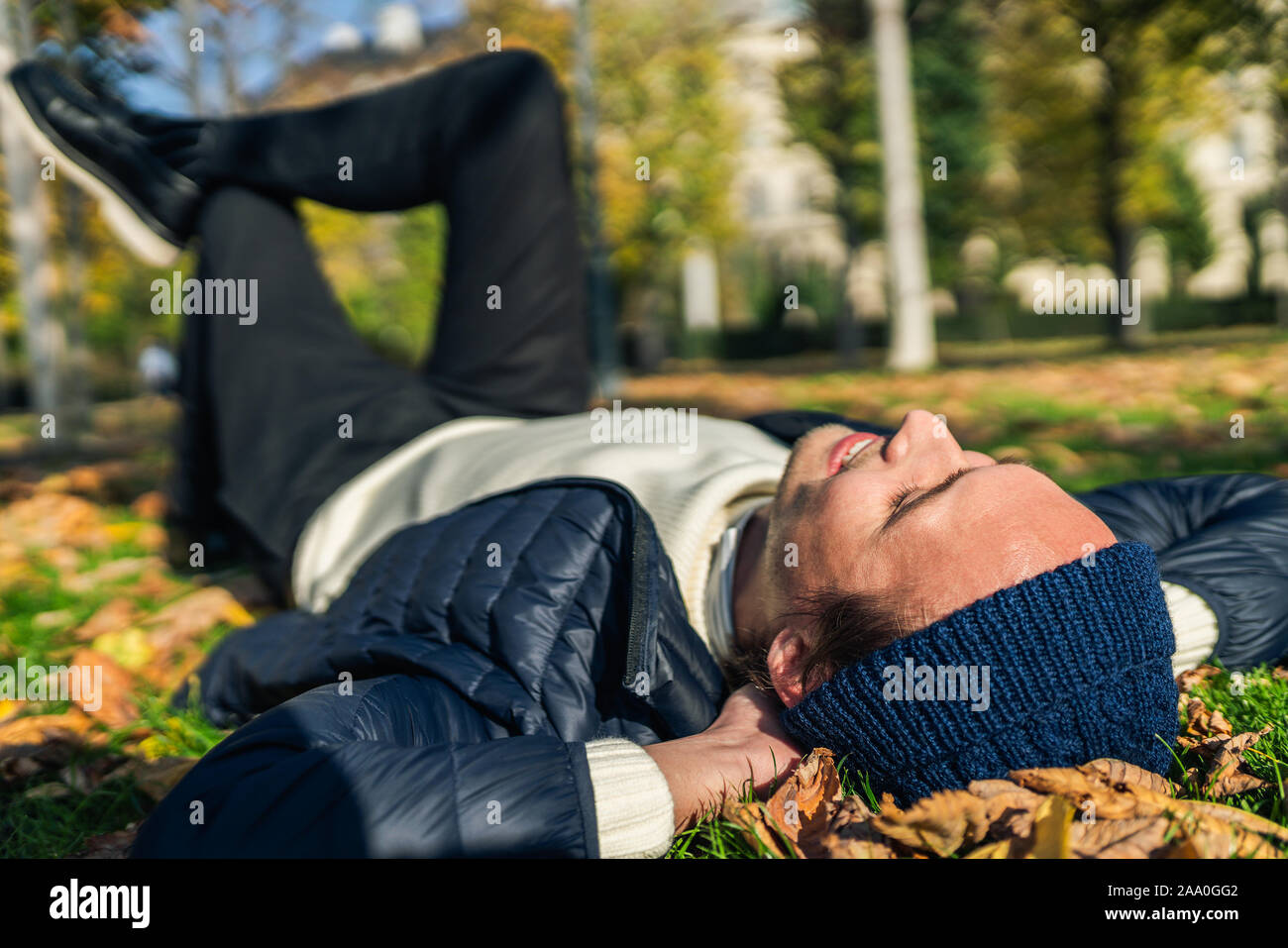 Felice giovane rilassante nel parco tra foglie di autunno. Foto Stock
