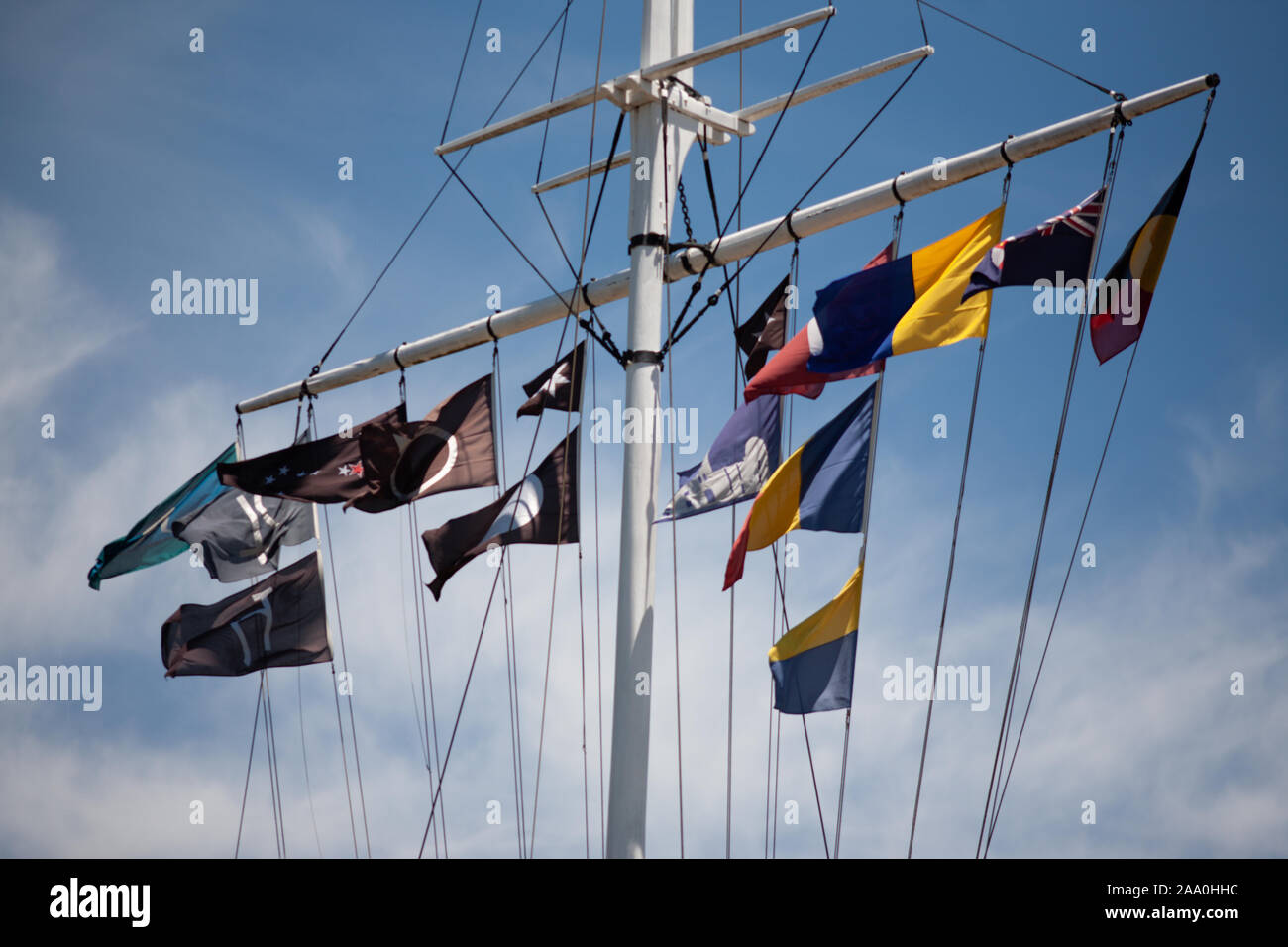 Bandiere colorate a volare su un montante in la brezza su un cielo blu giornata con wispy mentre le nuvole Foto Stock