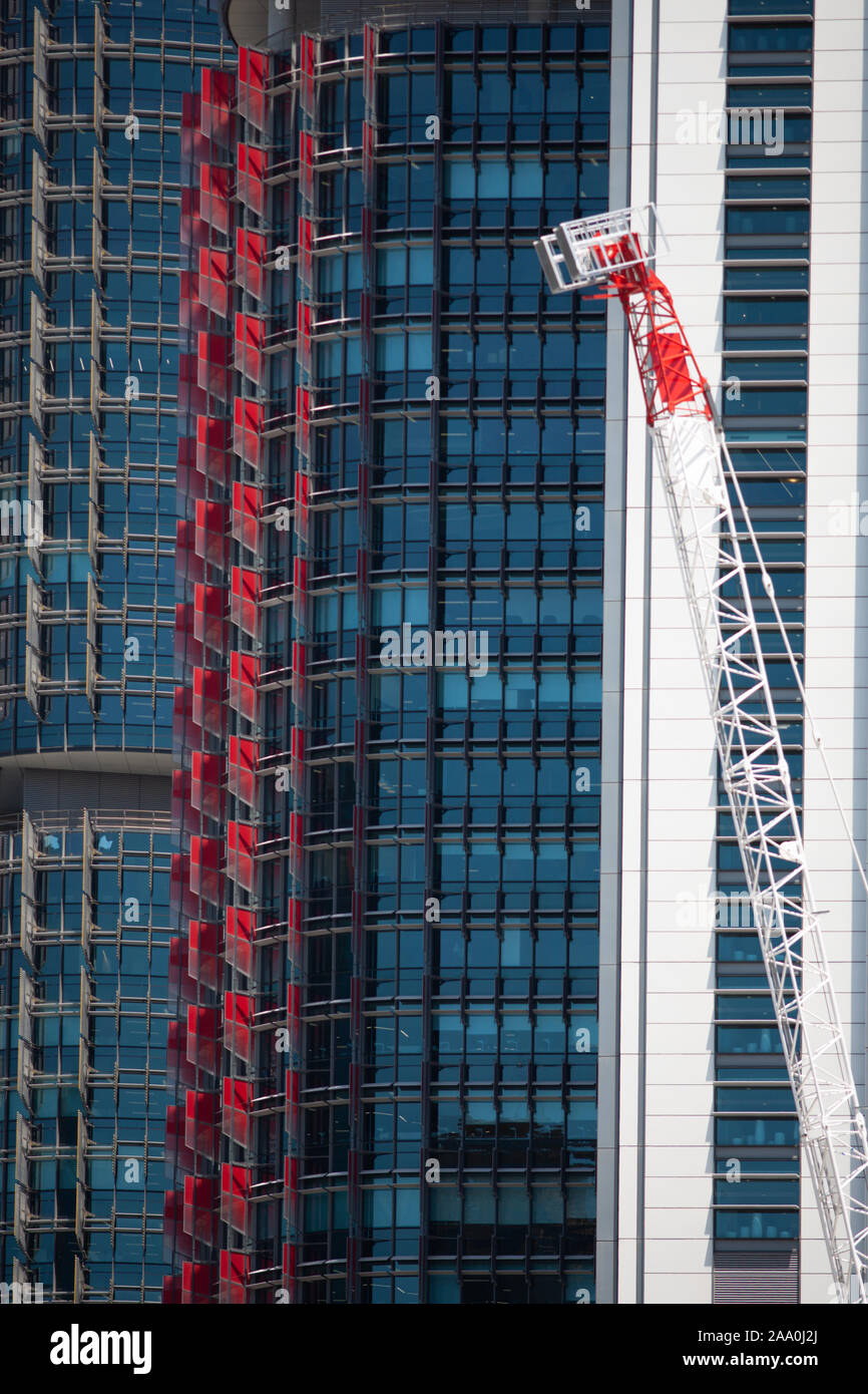 Il bianco e il rosso di gru di fronte alto e moderno sviluppo commerciale in una giornata di sole Foto Stock