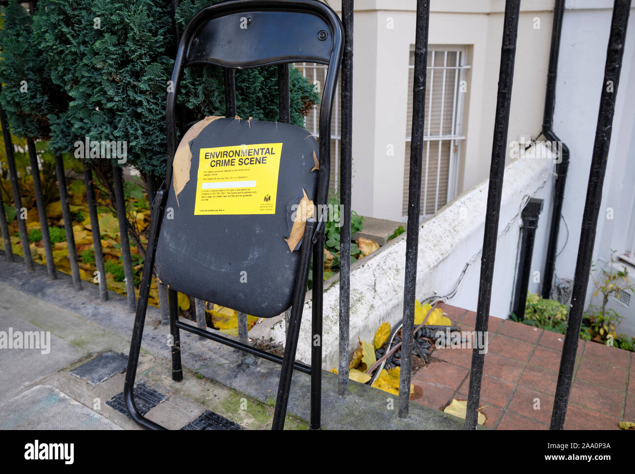 Sedia rotta per rifiuti lasciata non raccolta sul marciapiede con etichetta gialla "Environmental Crime Scene" dal distretto di Kensington e Chelsea, Foto Stock