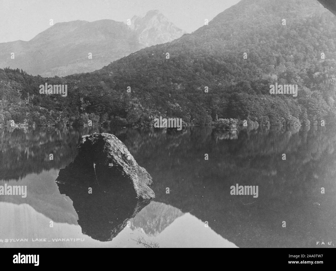 Bianco e nero fotografia paesaggio del lago Sylvan circondato da colline boscose, nella regione di Otago di South Island, in Nuova Zelanda, dal fotografo Frank Coxhead, 1885. Dalla Biblioteca Pubblica di New York. () Foto Stock
