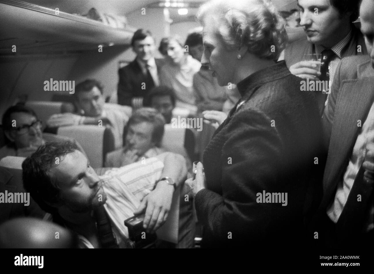 Sig.ra Margaret Thatcher, Inghilterra, circa giugno 1983. Campagna elettorale generale, durante il volo notturno di ritorno da Fleetwood, Lancashire, dove era stata campagna elettorale. La onorevole Thatcher parla con i membri della stampa itinerante. Il fotografo Herbie Knott la guarda in alto. OMERO SYKES Foto Stock