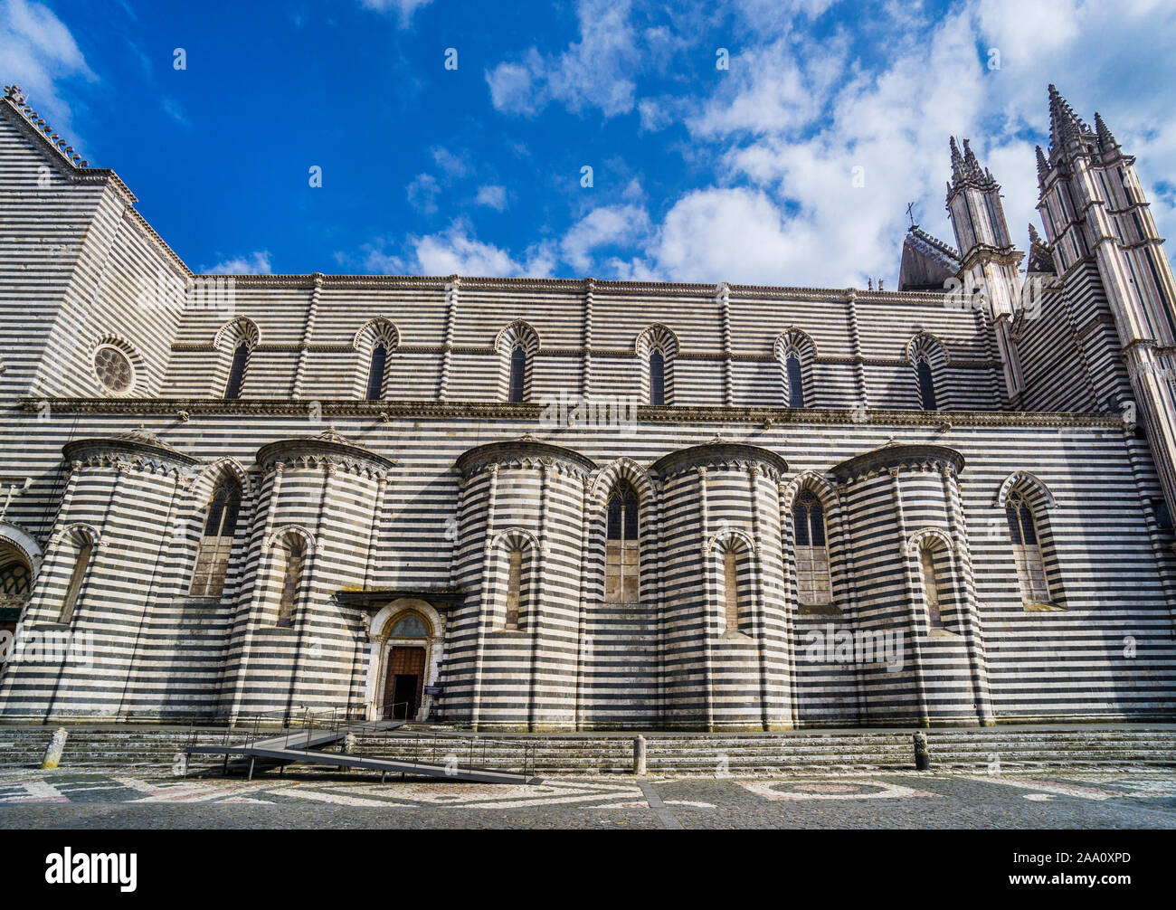 Vista del lato nord del Duomo di Orvieto da Piazza del Duomo, visualizzazione di strati alternati di travertino bianco e basalto scuro, Orvieto, Umbría Foto Stock